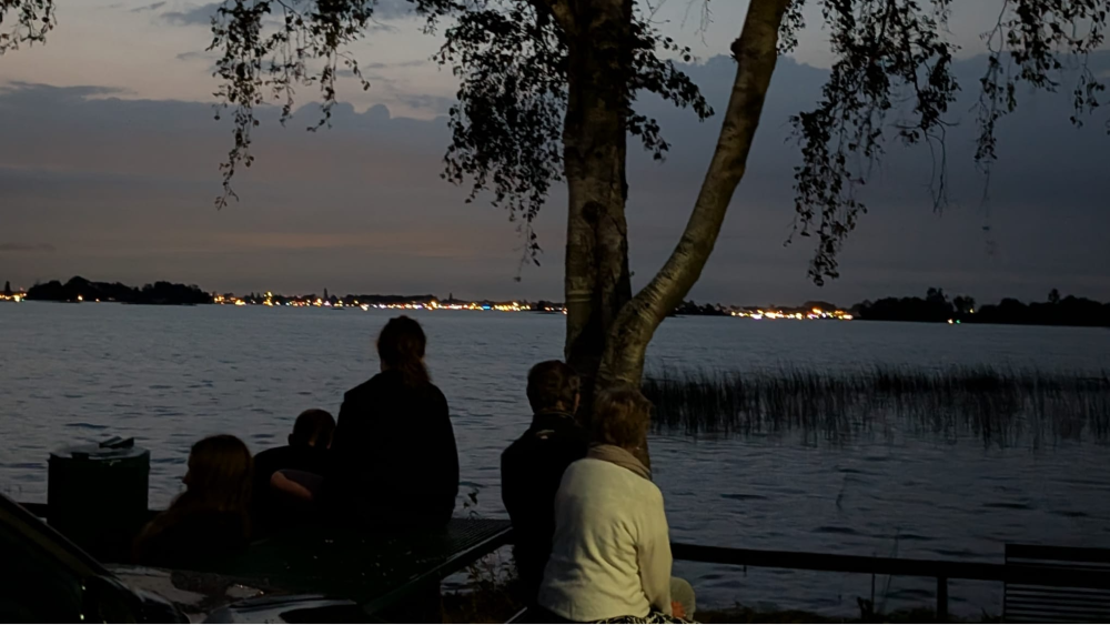 Bezoekers kijken in de verte naar de verlichte boten.
