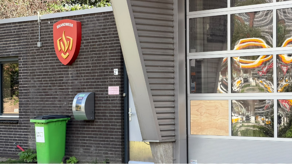 De deur van de kazerne. Een raam is vervangen door een houten plaat.