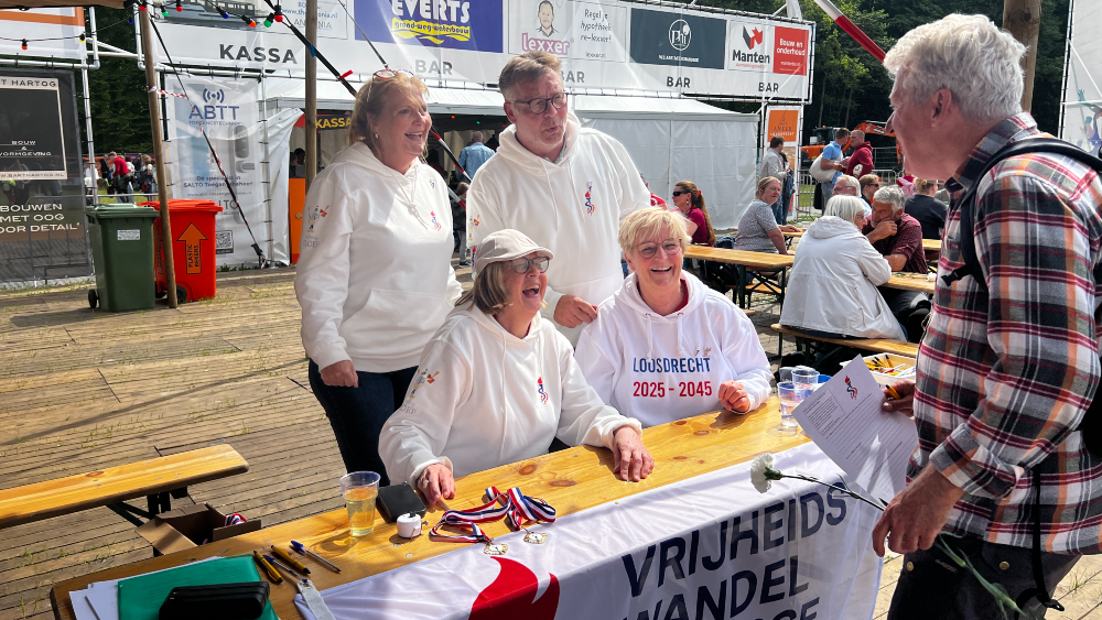 Deelnemer Fred krijgt een witte anjer en medaille bij de finish